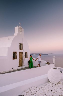 Santorini Yunanistan, genç çift güneş doğarken mavi kubbe kilisesi ve beyazlatılmış Oia Santorini köyünün gündoğumunu izlemek için Santorini Adası 'nda lüks bir tatile çıktılar.