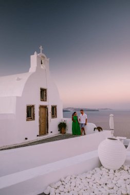 Santorini Yunanistan, genç çift güneş doğarken mavi kubbe kilisesi ve beyazlatılmış Oia Santorini köyünün gündoğumunu izlemek için Santorini Adası 'nda lüks bir tatile çıktılar.