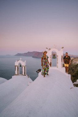 Santorini Yunanistan, genç çift güneş doğarken mavi kubbe kilisesi ve beyazlatılmış Oia Santorini köyünün gündoğumunu izlemek için Santorini Adası 'nda lüks bir tatile çıktılar.