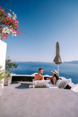 Santorini Yunanistan, genç çift güneş doğarken mavi kubbe kilisesi ve beyazlatılmış Oia Santorini köyünün gündoğumunu izlemek için Santorini Adası 'nda lüks bir tatile çıktılar.