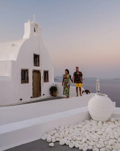 Santorini Grecia, giovane coppia in vacanza di lusso all'isola di Santorini guardando l'alba presso la chiesa cupola blu e il villaggio imbiancato di Oia Santorini Grecia durante l'alba — Foto Stock