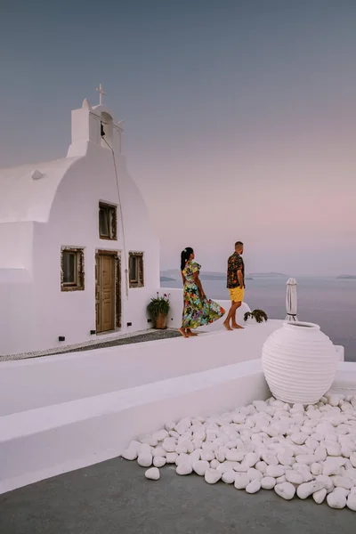 Santorini Grecia, giovane coppia in vacanza di lusso all'isola di Santorini guardando l'alba presso la chiesa cupola blu e il villaggio imbiancato di Oia Santorini Grecia durante l'alba — Foto Stock