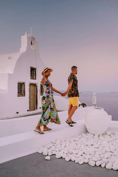 Santorini Grecia, giovane coppia in vacanza di lusso all'isola di Santorini guardando l'alba presso la chiesa cupola blu e il villaggio imbiancato di Oia Santorini Grecia durante l'alba — Foto Stock