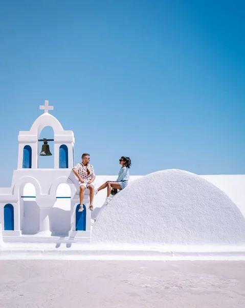 Σαντορίνη Ελλάδα, νεαρό ζευγάρι σε πολυτελείς διακοπές στο νησί της Σαντορίνης βλέποντας την ανατολή του ηλίου από την εκκλησία του γαλάζιου θόλου και το ασβεστωμένο χωριό της Οίας Σαντορίνη Ελλάδα κατά την ανατολή του ηλίου, άνδρες και γυναίκες σε — Φωτογραφία Αρχείου