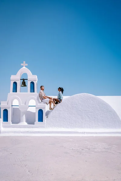 Santorini Grecia, giovane coppia in vacanza di lusso all'isola di Santorini guardando l'alba dalla chiesa cupola blu e villaggio imbiancato di Oia Santorini Grecia durante l'alba, uomini e donne su — Foto Stock