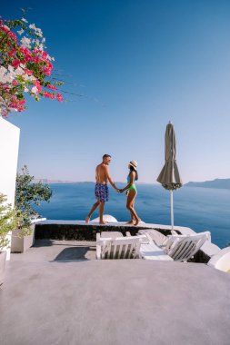 Santorini Yunanistan, genç çift güneş doğarken mavi kubbe kilisesi ve beyazlatılmış Oia Santorini köyünün gündoğumunu izlemek için Santorini Adası 'nda lüks bir tatile çıktılar.