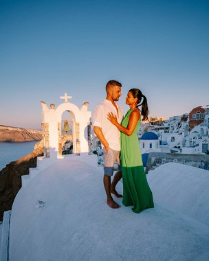 Santorini Yunanistan, genç çift güneş doğarken mavi kubbe kilisesi ve beyazlatılmış Oia Santorini köyünün gündoğumunu izlemek için Santorini Adası 'nda lüks bir tatile çıktılar.