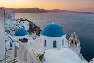 Yunanistan 'ın Santorini Adası' nda gün batımı, güzel, bembeyaz bir köy olan Oia 'da gün batımında kilise ve yel değirmeni.