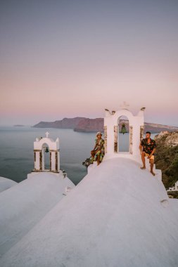 Santorini Yunanistan, genç çift güneş doğarken mavi kubbe kilisesi ve beyazlatılmış Oia Santorini köyünün gündoğumunu izlemek için Santorini Adası 'nda lüks bir tatile çıktılar.