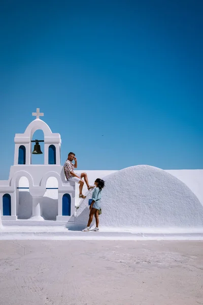 Santorini Grecia, giovane coppia in vacanza di lusso all'isola di Santorini guardando l'alba dalla chiesa cupola blu e villaggio imbiancato di Oia Santorini Grecia durante l'alba, uomini e donne su — Foto Stock
