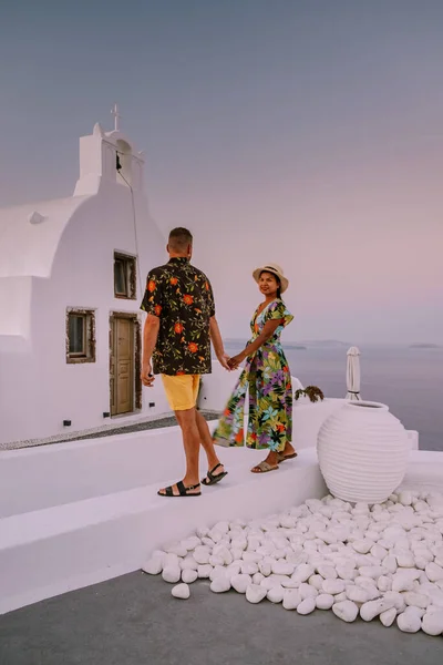 Santorini Grecia, giovane coppia in vacanza di lusso all'isola di Santorini guardando l'alba presso la chiesa cupola blu e il villaggio imbiancato di Oia Santorini Grecia durante l'alba — Foto Stock