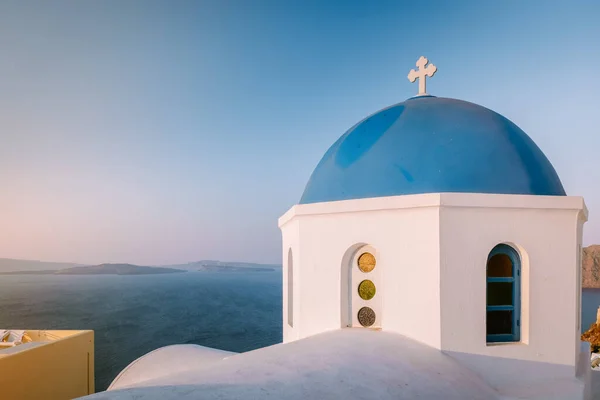 Puesta de sol en la isla de Santorini Grecia, hermoso pueblo encalado Oia con iglesia y molino de viento durante la puesta del sol — Foto de Stock