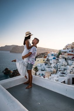Santorini Yunanistan, genç çift güneş doğarken mavi kubbe kilisesi ve beyazlatılmış Oia Santorini köyünün gündoğumunu izlemek için Santorini Adası 'nda lüks bir tatile çıktılar.