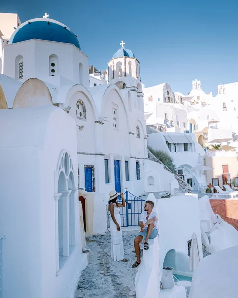 Santorini Griechenland, junges Paar im Luxusurlaub auf der Insel Santorini beim Sonnenaufgang an der blauen Kuppelkirche und dem weiß getünchten Dorf Oia Santorini Griechenland, Männer und Frauen bei Sonnenaufgang — Stockfoto