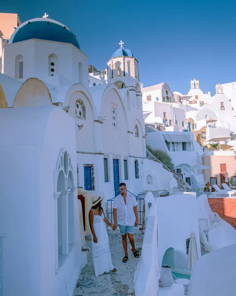 Santorini Grecia, pareja joven en vacaciones de lujo en la isla de Santorini viendo el amanecer por la iglesia de cúpula azul y el pueblo encalado de Oia Santorini Grecia durante el amanecer, hombres y mujeres en — Foto de Stock