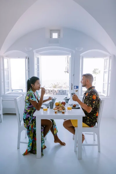 Petit déjeuner dans la grotte historique traditionnelle, Santorin Grèce, jeune couple en vacances de luxe à l'île de Santorin en regardant le lever du soleil près de l'église à dôme bleu et village blanchie à la chaux d'Oia — Photo