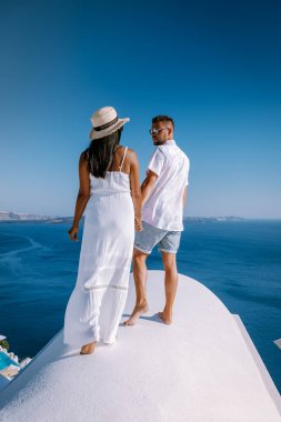 Santorini 'de tatilde olan çift erkek ve kadın, denize bakıyor ve Yunanistan' ın Santorini adasının başkenti Fira 'dan yanardağ.