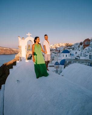 Santorini Yunanistan, genç çift güneş doğarken mavi kubbe kilisesi ve beyazlatılmış Oia Santorini köyünün gündoğumunu izlemek için Santorini Adası 'nda lüks bir tatile çıktılar.