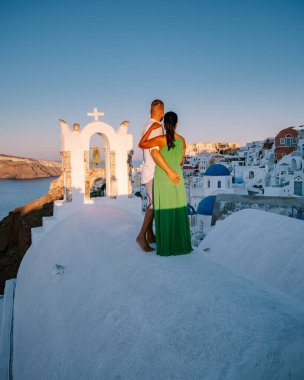 Santorini Yunanistan, genç çift güneş doğarken mavi kubbe kilisesi ve beyazlatılmış Oia Santorini köyünün gündoğumunu izlemek için Santorini Adası 'nda lüks bir tatile çıktılar.