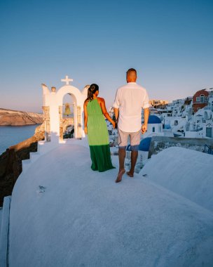 Santorini Yunanistan, genç çift güneş doğarken mavi kubbe kilisesi ve beyazlatılmış Oia Santorini köyünün gündoğumunu izlemek için Santorini Adası 'nda lüks bir tatile çıktılar.