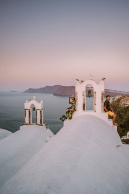 Santorini Yunanistan, genç çift güneş doğarken mavi kubbe kilisesi ve beyazlatılmış Oia Santorini köyünün gündoğumunu izlemek için Santorini Adası 'nda lüks bir tatile çıktılar.