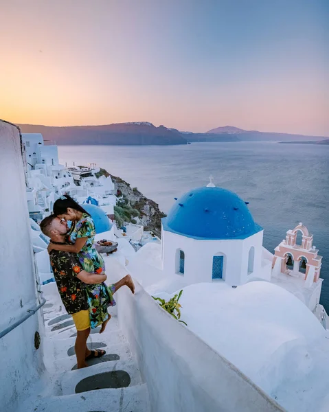 Santorini Yunanistan, genç çift güneş doğarken mavi kubbe kilisesi ve beyazlatılmış Oia Santorini köyünün gündoğumunu izlemek için Santorini Adası 'nda lüks bir tatile çıktılar. — Stok fotoğraf