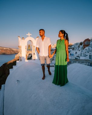 Santorini Yunanistan, genç çift güneş doğarken mavi kubbe kilisesi ve beyazlatılmış Oia Santorini köyünün gündoğumunu izlemek için Santorini Adası 'nda lüks bir tatile çıktılar.