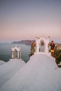 Santorini Yunanistan, genç çift güneş doğarken mavi kubbe kilisesi ve beyazlatılmış Oia Santorini köyünün gündoğumunu izlemek için Santorini Adası 'nda lüks bir tatile çıktılar.