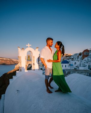 Santorini Yunanistan, genç çift güneş doğarken mavi kubbe kilisesi ve beyazlatılmış Oia Santorini köyünün gündoğumunu izlemek için Santorini Adası 'nda lüks bir tatile çıktılar.