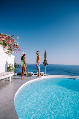 Santorini Yunanistan, genç çift güneş doğarken mavi kubbe kilisesi ve beyazlatılmış Oia Santorini köyünün gündoğumunu izlemek için Santorini Adası 'nda lüks bir tatile çıktılar.