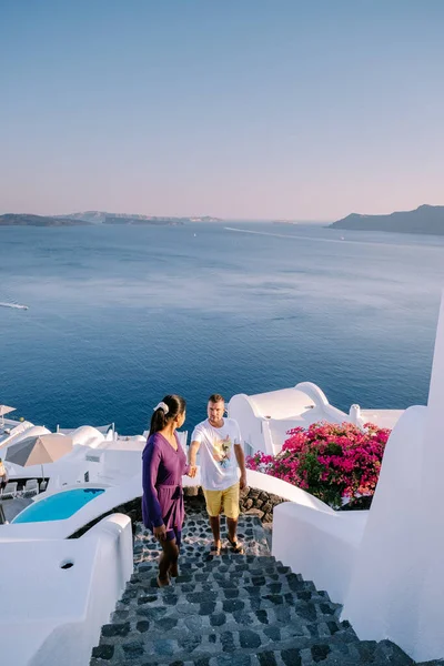 Santorini Greece, young couple on luxury vacation at the Island of Santorini watching sunrise by the blue dome church and whitewashed village of Oia Santorini Greece during sunrise, men and woman on — Stock Photo, Image