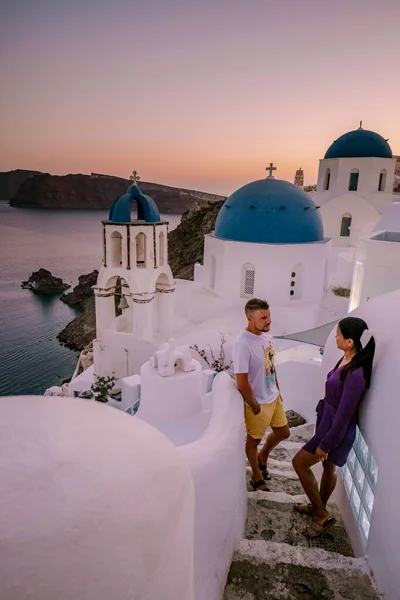 Santorini Griechenland, junges Paar im Luxusurlaub auf der Insel Santorini beim Sonnenaufgang an der blauen Kuppelkirche und dem weiß getünchten Dorf Oia Santorini Griechenland — Stockfoto