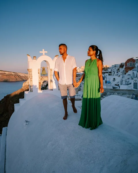 Santorini Grécia, jovem casal em férias de luxo na Ilha de Santorini assistindo ao nascer do sol pela igreja cúpula azul e aldeia caiada de branco de Oia Santorini Grécia durante o nascer do sol, homens e mulheres em — Fotografia de Stock