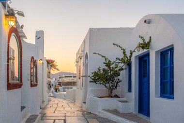 Yunanistan 'ın Santorini Adası' nda gün batımı, güzel, bembeyaz bir köy olan Oia 'da gün batımında kilise ve yel değirmeni.