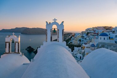 Yunanistan 'ın Santorini Adası' nda gün batımı, güzel, bembeyaz bir köy olan Oia 'da gün batımında kilise ve yel değirmeni.