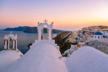 Yunanistan 'ın Santorini Adası' nda gün batımı, güzel, bembeyaz bir köy olan Oia 'da gün batımında kilise ve yel değirmeni.