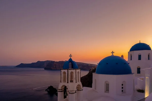 Puesta de sol en la isla de Santorini Grecia, hermoso pueblo encalado Oia con iglesia y molino de viento durante la puesta del sol — Foto de Stock