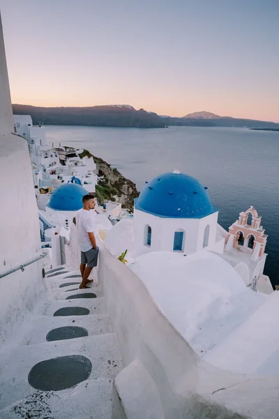 Sunset at the Island Of Santorini Greece, beautiful whitewashed village Oia with church and windmill during sunset, young men on luxury vacation Santorini — Stock Photo, Image