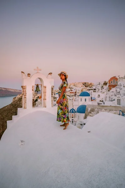 Yunanistan 'ın Santorini Adası' nda gün batımı, güzel, bembeyaz bir köy. Günbatımında kilise ve yel değirmeni olan Oia. Yunanistan 'da lüks tatilde olan bir kadın. — Stok fotoğraf