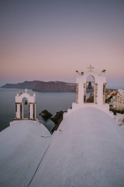 Yunanistan 'ın Santorini Adası' nda gün batımı, güzel, bembeyaz bir köy olan Oia 'da gün batımında kilise ve yel değirmeni.