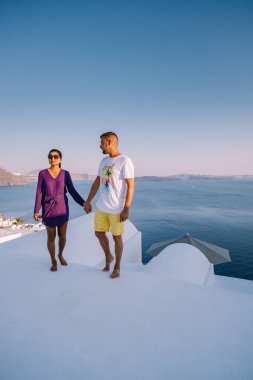 Santorini Yunanistan, genç çift güneş doğarken mavi kubbe kilisesi ve beyazlatılmış Oia Santorini köyünün gündoğumunu izlemek için Santorini Adası 'nda lüks bir tatile çıktılar.