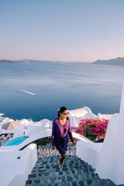 Yunanistan 'ın Santorini Adası' nda gün batımı, güzel, bembeyaz bir köy. Günbatımında kilise ve yel değirmeni olan Oia. Yunanistan 'da lüks tatilde olan bir kadın. — Stok fotoğraf