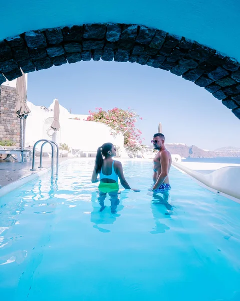 Santorini Grecia, pareja joven en vacaciones de lujo en la isla de Santorini viendo el amanecer por la iglesia de cúpula azul y el pueblo encalado de Oia Santorini Grecia durante el amanecer, hombres y mujeres en — Foto de Stock