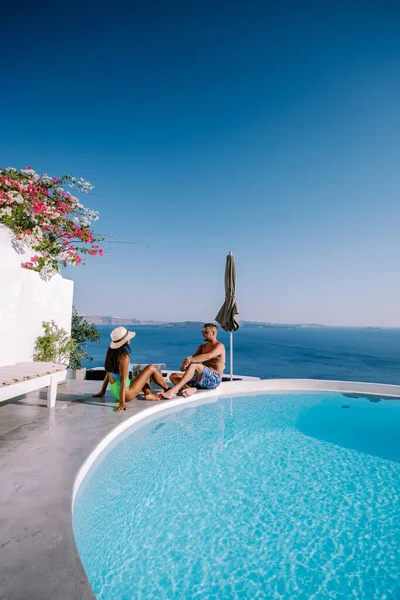 Santorini Greece, young couple on luxury vacation at the Island of Santorini watching sunrise by the blue dome church and whitewashed village of Oia Santorini Greece during sunrise, men and woman on Royalty Free Stock Photos