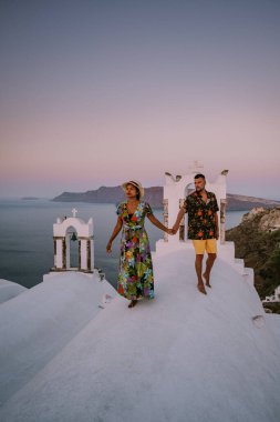 Santorini Yunanistan, genç çift güneş doğarken mavi kubbe kilisesi ve beyazlatılmış Oia Santorini köyünün gündoğumunu izlemek için Santorini Adası 'nda lüks bir tatile çıktılar.