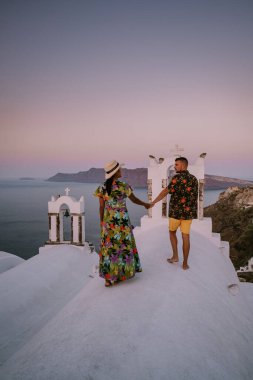 Santorini Yunanistan, genç çift güneş doğarken mavi kubbe kilisesi ve beyazlatılmış Oia Santorini köyünün gündoğumunu izlemek için Santorini Adası 'nda lüks bir tatile çıktılar.