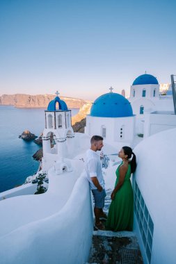 Santorini Yunanistan, genç çift güneş doğarken mavi kubbe kilisesi ve beyazlatılmış Oia Santorini köyünün gündoğumunu izlemek için Santorini Adası 'nda lüks bir tatile çıktılar.