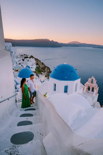 Santorini Griechenland, junges Paar im Luxusurlaub auf der Insel Santorini beim Sonnenaufgang an der blauen Kuppelkirche und dem weiß getünchten Dorf Oia Santorini Griechenland, Männer und Frauen bei Sonnenaufgang — Stockfoto