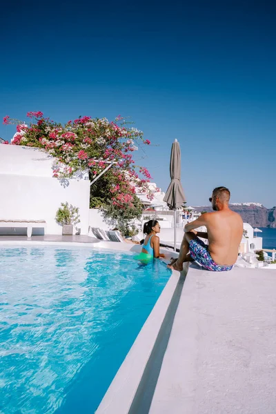 Santorini Grecia, pareja joven en vacaciones de lujo en la isla de Santorini viendo el amanecer por la iglesia de cúpula azul y el pueblo encalado de Oia Santorini Grecia durante el amanecer, hombres y mujeres en —  Fotos de Stock