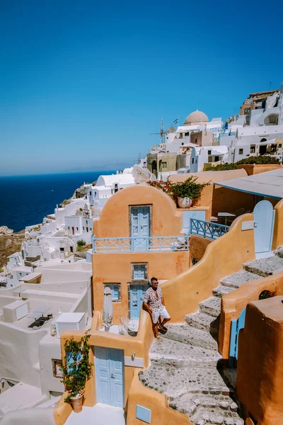 Santorini Griechenland, junger Mann im Luxusurlaub auf der Insel Santorini, der den Sonnenaufgang an der blauen Kuppelkirche und dem weiß getünchten Dorf Oia Santorini Griechenland bei Sonnenaufgang beobachtet, Männer und Frauen auf — Stockfoto